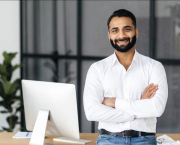 man with arms crossed sitting by his computer